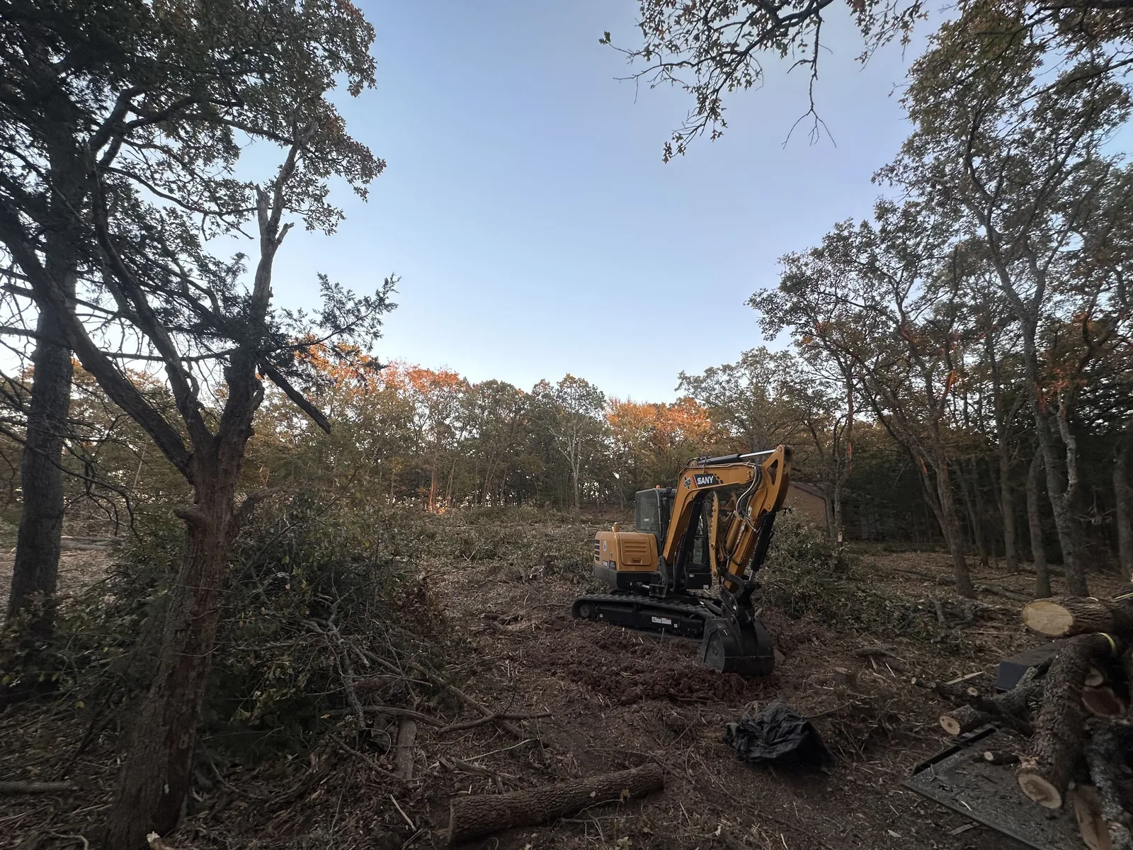Excavator working beside an outbuilding on a rural Oklahoma property