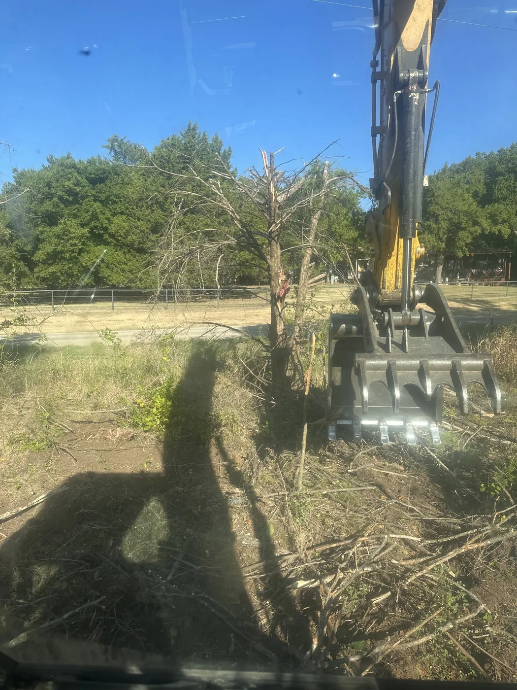 Excavator grapple moving brush and debris during excavation work near Ada, OK