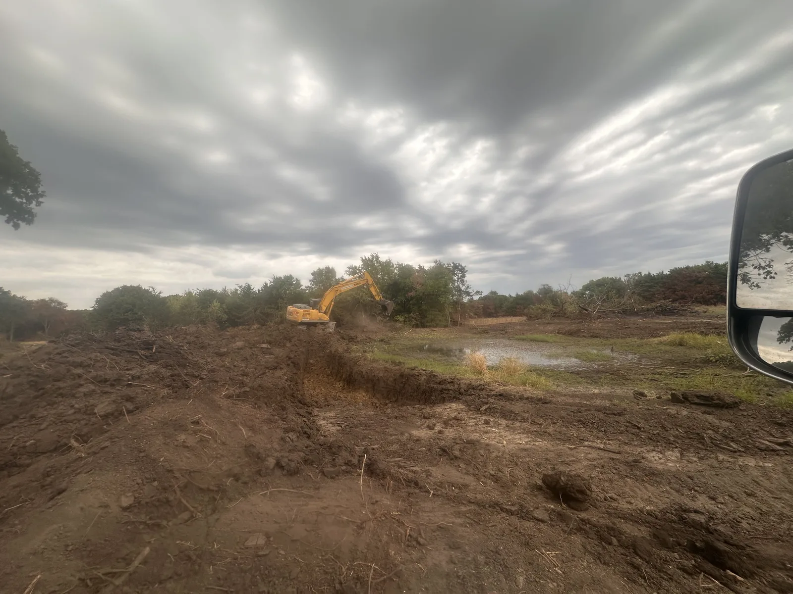 Our excavator digging the pond under an overcast sky