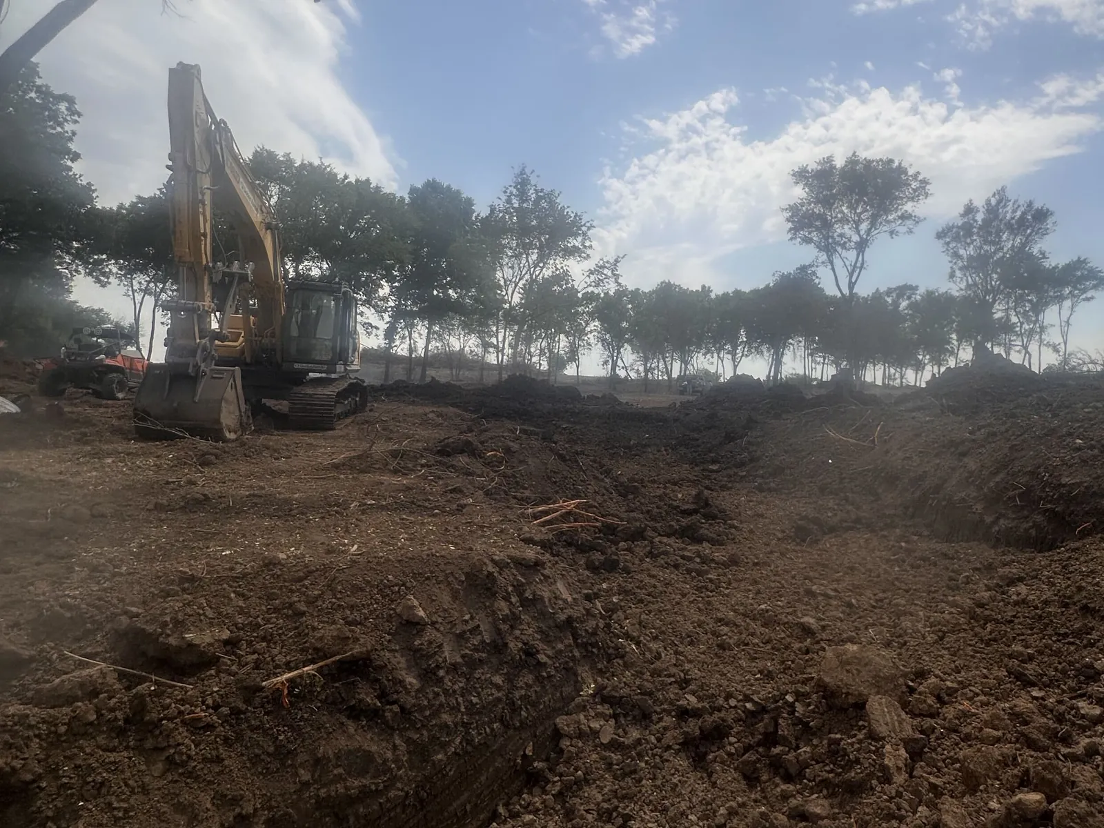 Excavator working an old pond basin during a cleanout on one of our Oklahoma pond jobs